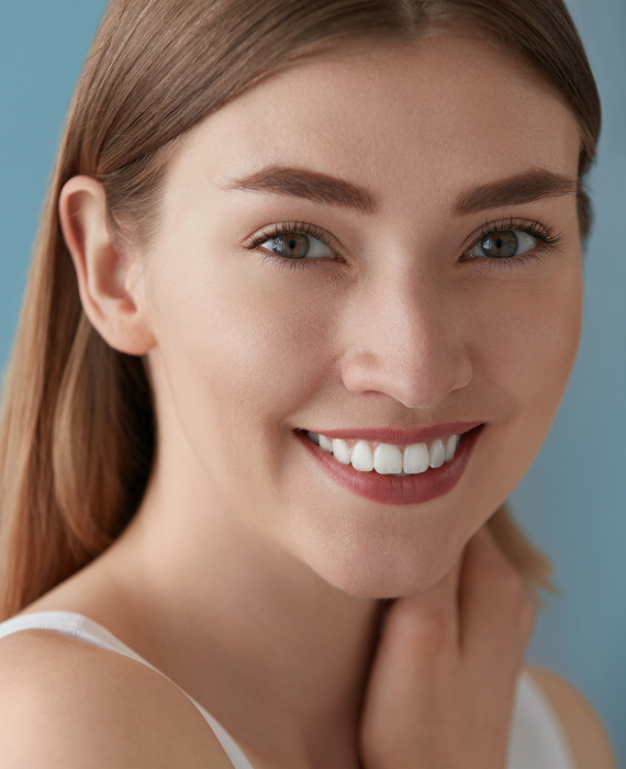 Smiling woman looking into mirror brushing her teeth smoothly